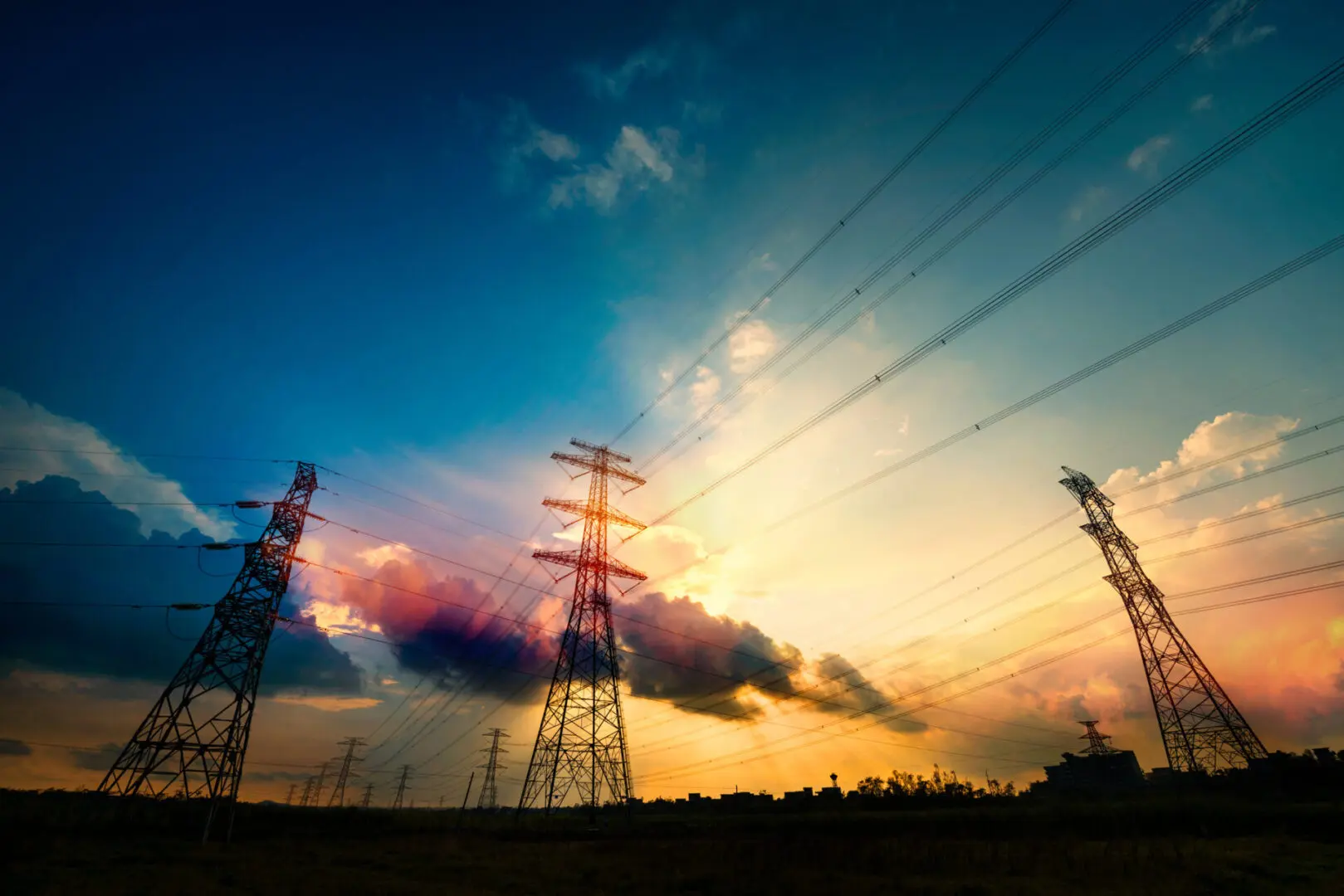 Sunset behind silhouetted power lines and towers.