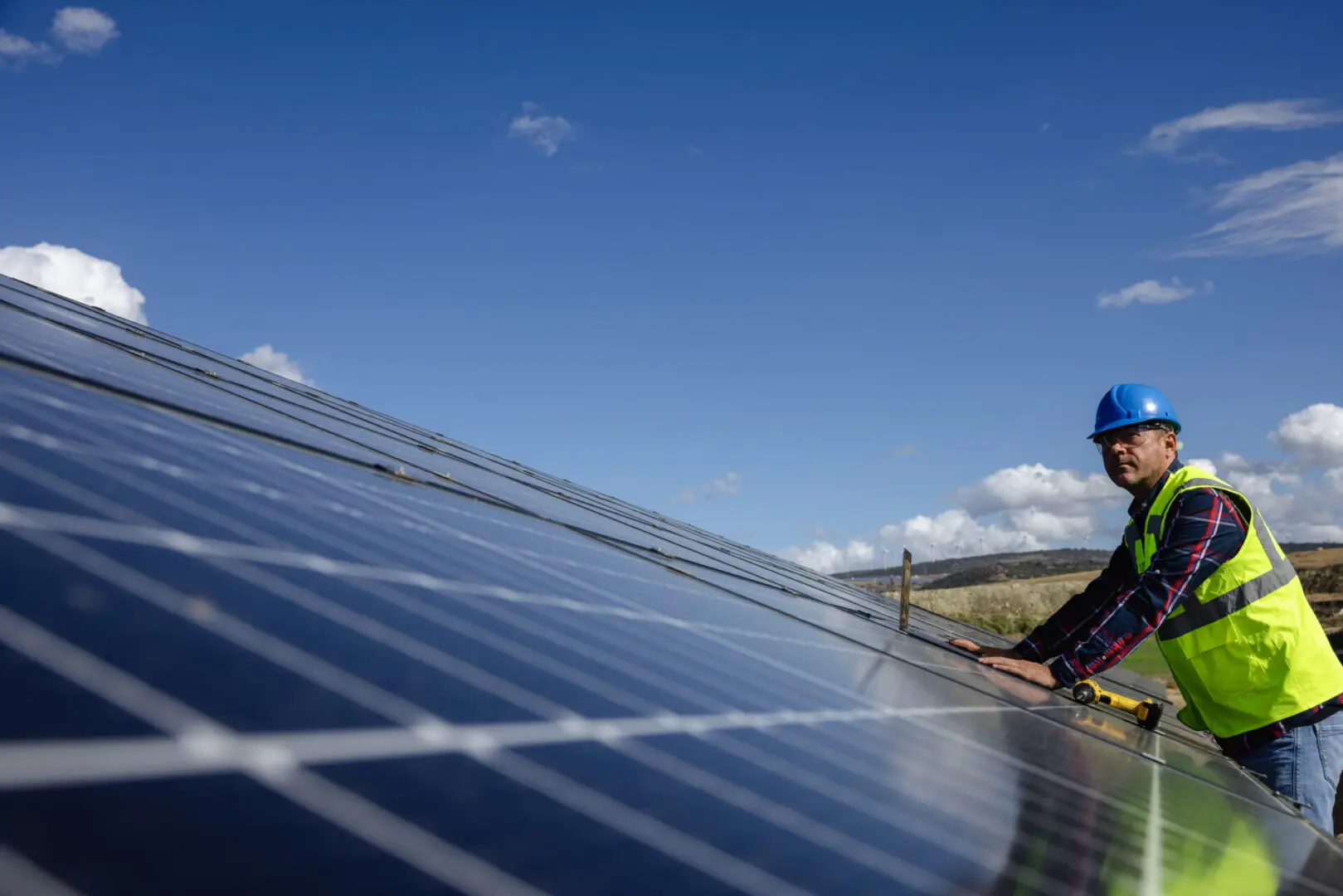 Worker inspecting large solar panel installation.