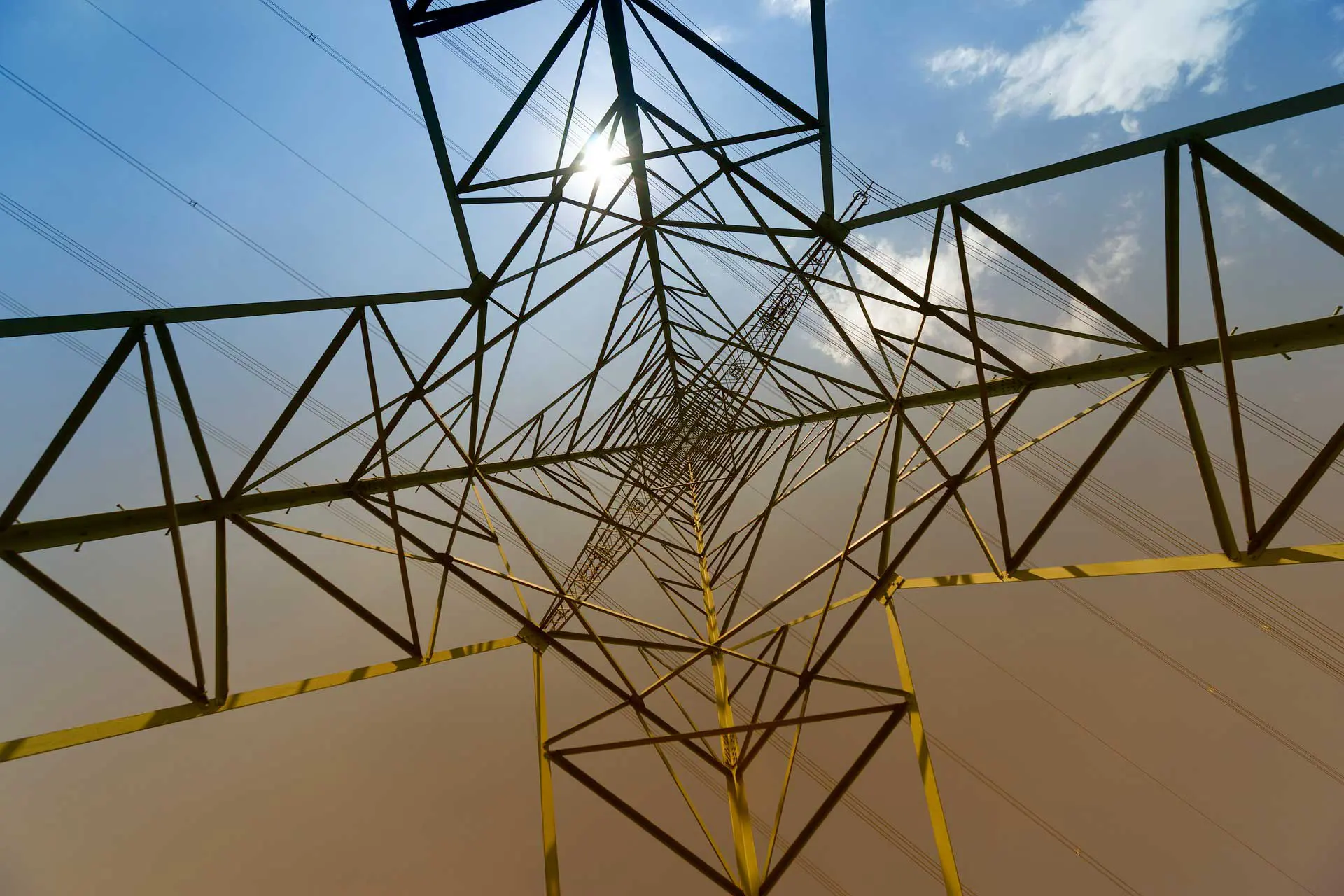 Looking up at metal power transmission tower.