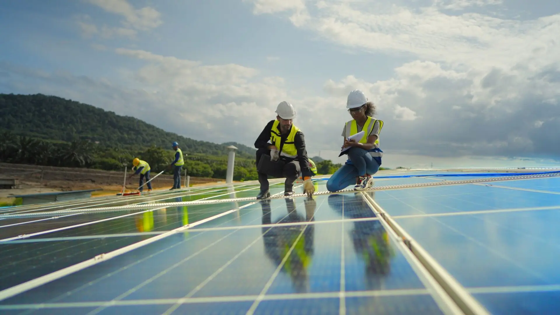 Workers inspecting solar panels on rooftop.