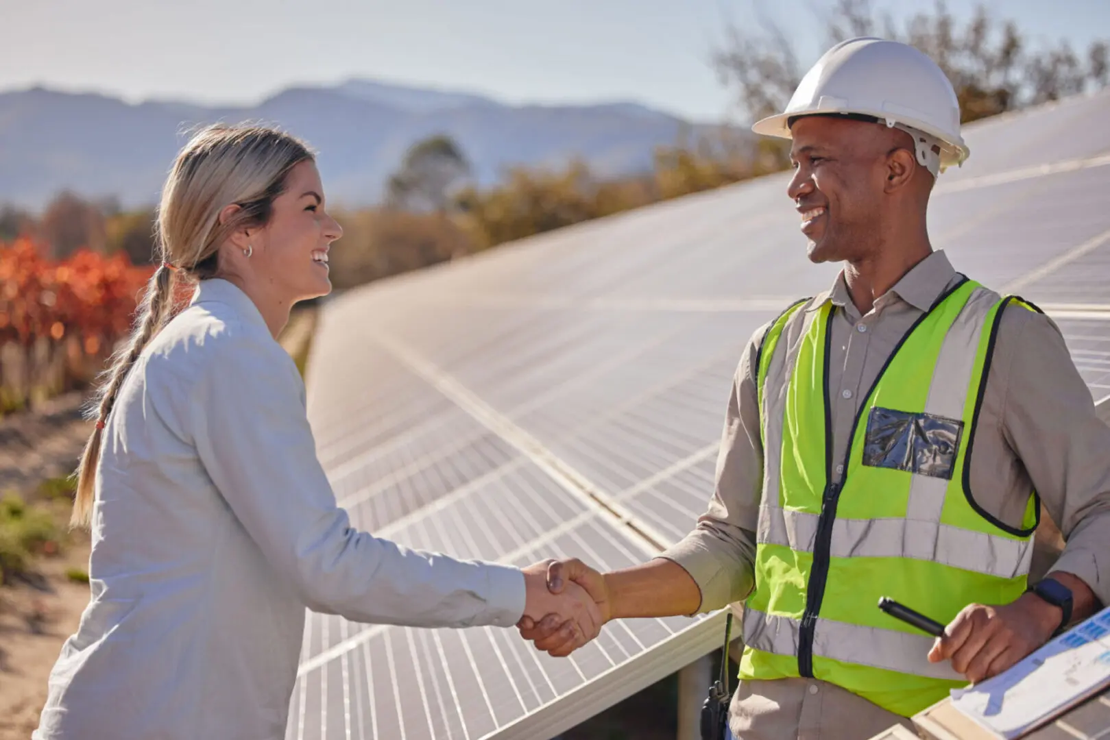 Two people shaking hands near solar panels.