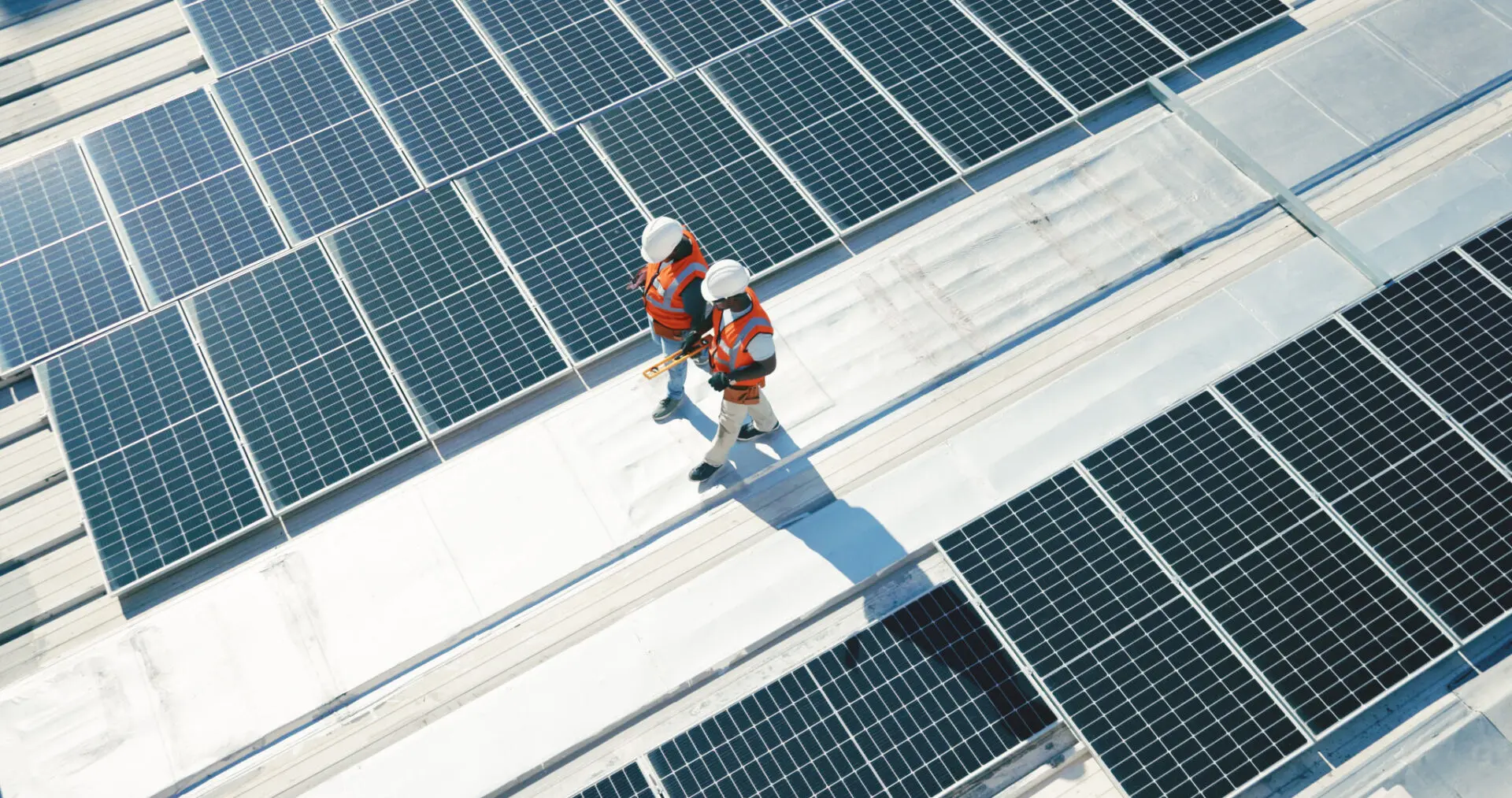 Workers inspecting rooftop solar panel installation.